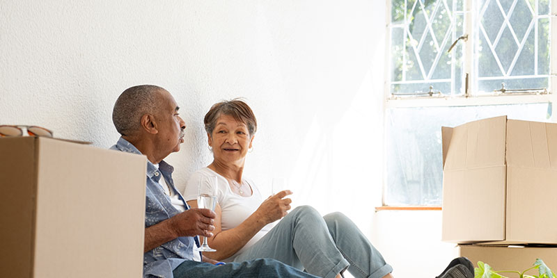 Older couple sitting together, celebrating in a new home.