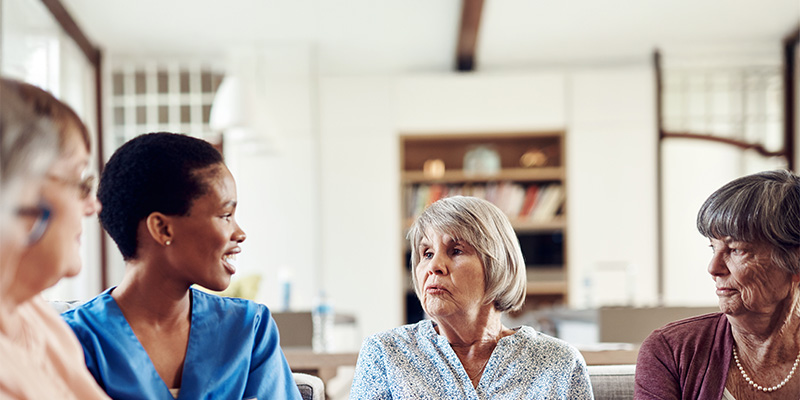 Cropped shot of a young nurse sitting with her senior patients in the living room of a nursing home