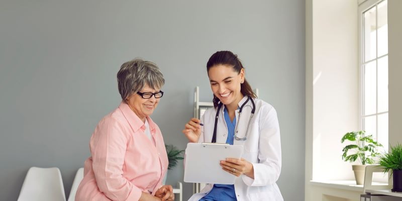 A doctor sits and talks with an older woman