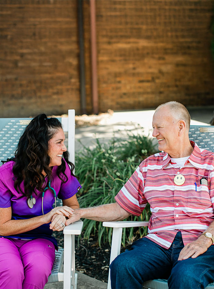 Two people seated outdoors, sharing a friendly conversation.