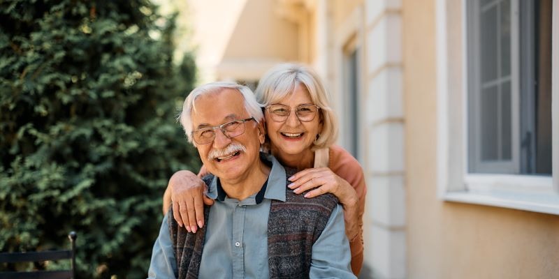 Happy elderly couple posing outdoors, smiling together.