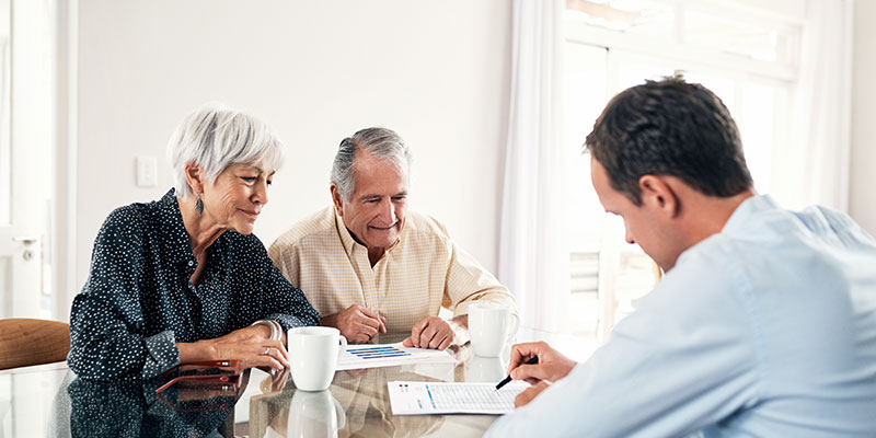 Three people discussing papers at a table.