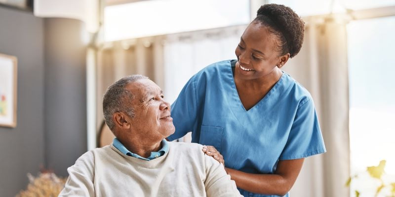 Caregiver and elderly man share a warm, friendly moment.